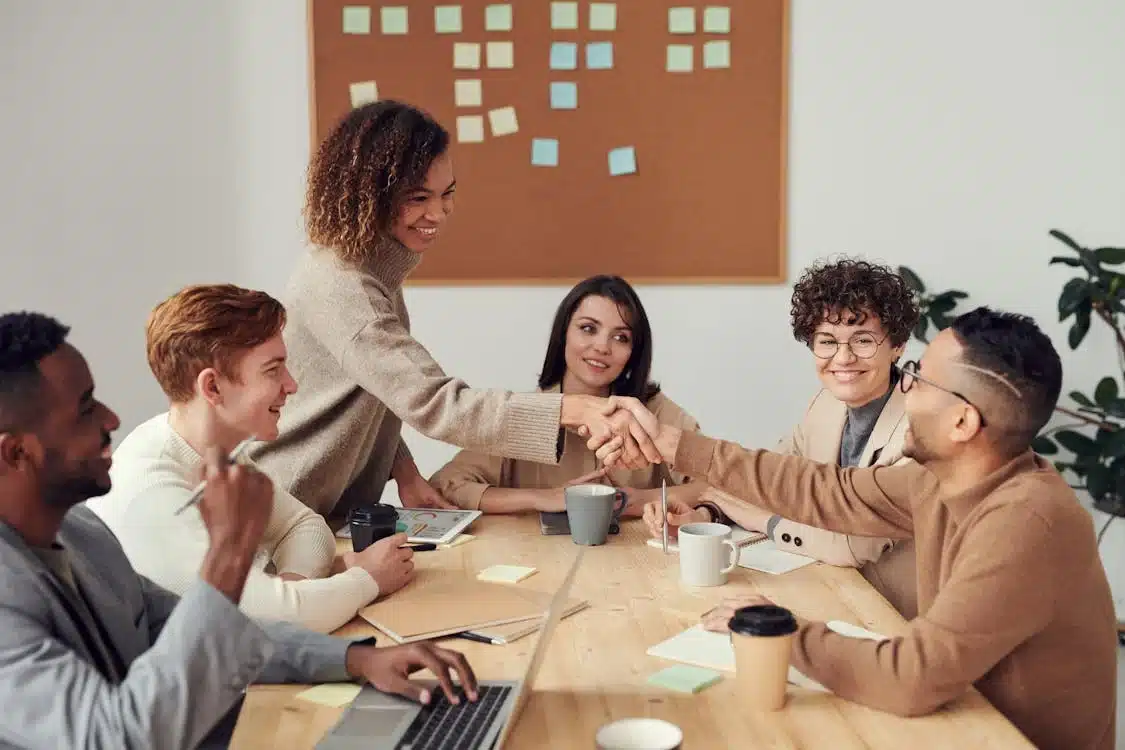 Team members shaking hands in a meeting, demonstrating collaboration and strong work ethics.