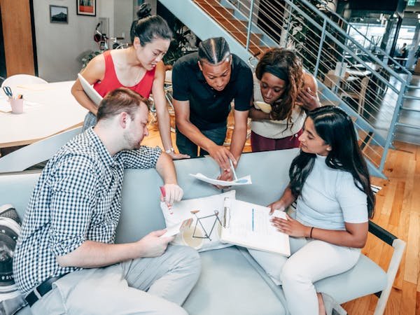 a group of people sitting on a couch looking at papers - dei principles