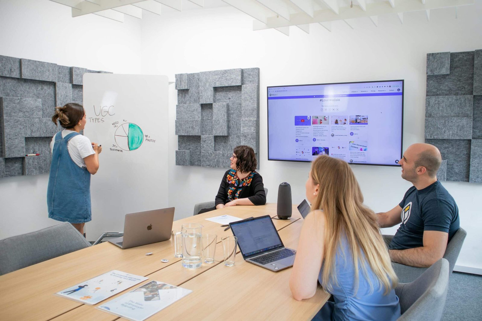 Team discussing strategies with a whiteboard and screen, related to Growth Hacking vs Digital Marketing.