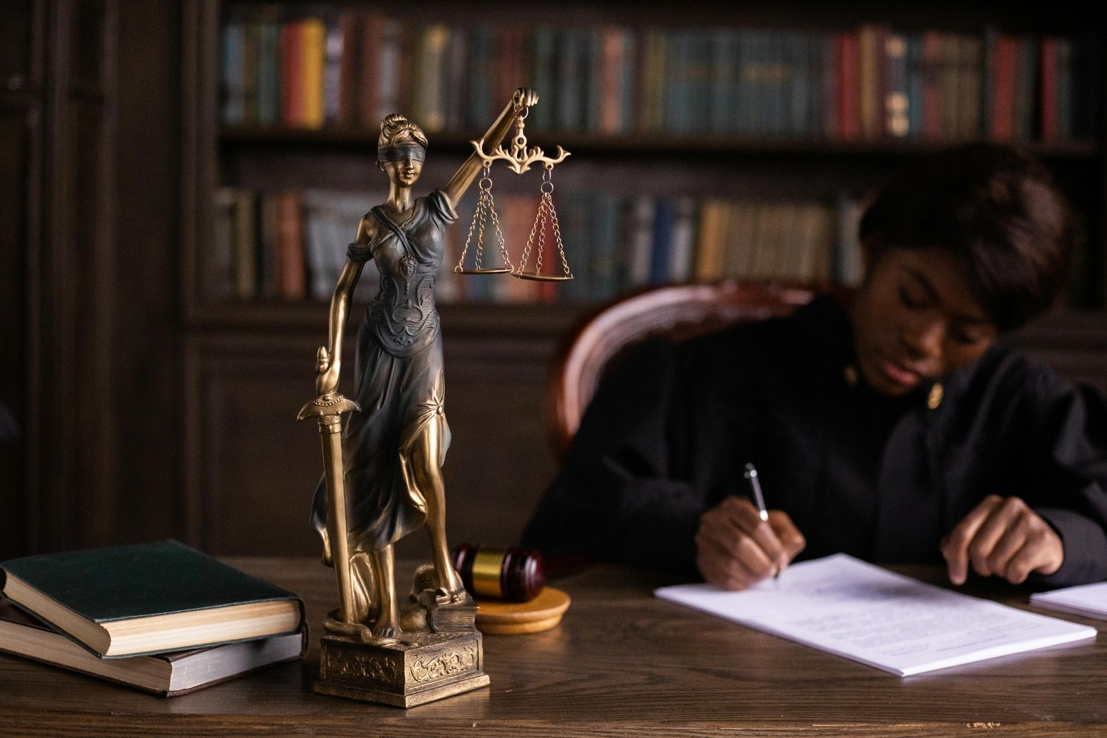 Judge writing at desk with Lady Justice statue, reflecting legal limitations on freedom of speech.
