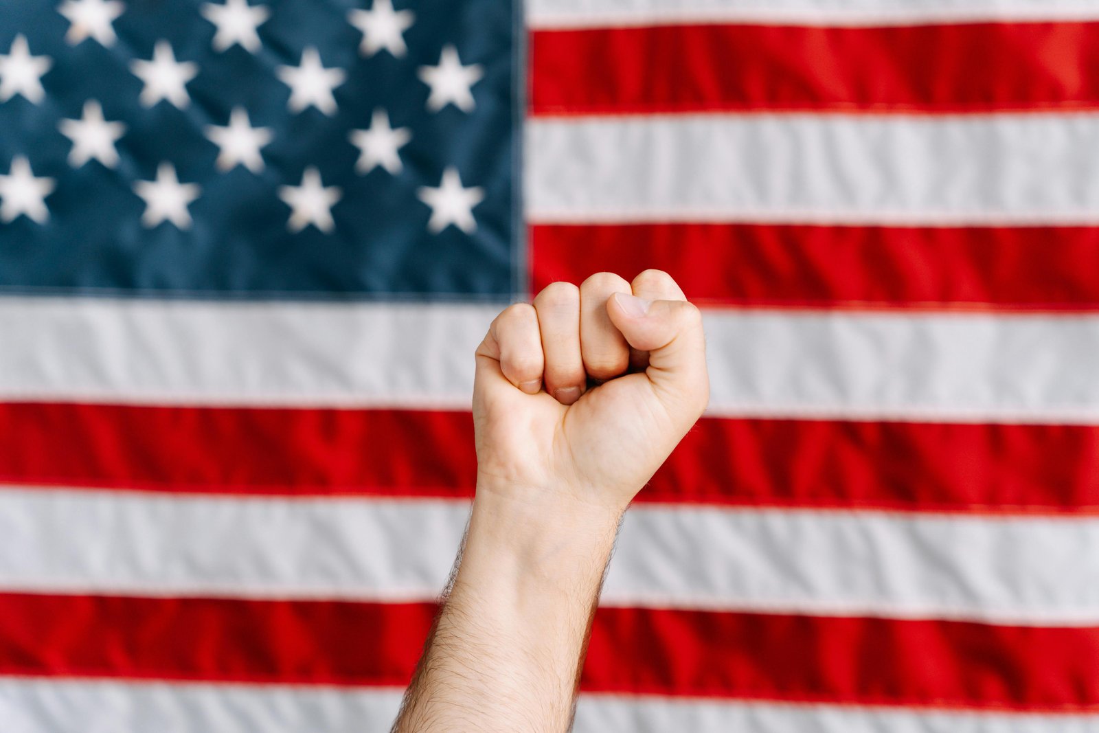 Raised fist in front of the American flag symbolizing respect for traditional values and national pride.